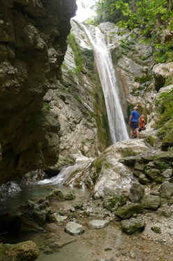 Zwei Personen stehen vor dem Wasserfall in der Nähe von Nidri auf der Insel Lefkas