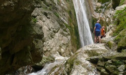 Zwei Personen stehen vor dem Wasserfall in der Nähe von Nidri auf der Insel Lefkas