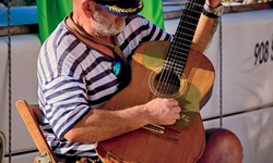 Ein Einheimischer Kapitan, der mit der auf einem Stuhl sitzt und mit einer Gitarre spielt