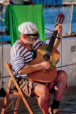 Ein Einheimischer Kapitan, der mit der auf einem Stuhl sitzt und mit einer Gitarre spielt