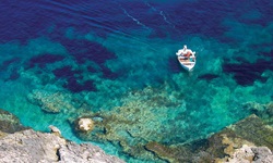 Ein Boot mit einem Mann in einer Bucht mit türkisblauem Wasser und Blick auf den Untergrund