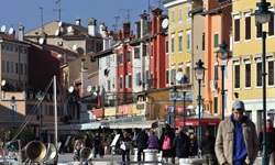 Touristen vor den bunten Häusern einer Gasse am Hafen von Rovinj.