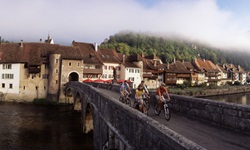 Vier Radfahrer auf der Jura-Route überqueren eine Brücke.