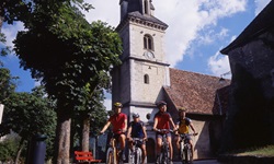 Vier Radfahrer radeln auf der Jura-Route an einer Kirche vorbei.