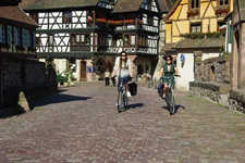Zwei Radlerinnen fahren durch Kaysersberg auf Kopfsteinpflaster