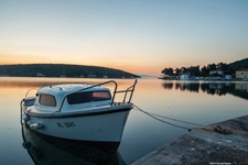 Ein kleines Boot dümpelt im Abendlicht in einem Hafen der Kvarner Bucht.