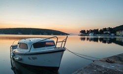 Ein kleines Boot dümpelt im Abendlicht in einem Hafen der Kvarner Bucht.