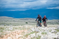 Zwei Mountainbiker fahren auf einem steinigen Naturweg über eine Insel der Kvarner Bucht.