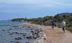 Fahrradfahrer radeln auf einem Kiesweg auf der Insel Losinj am Meer entlang