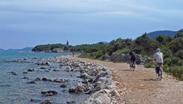 Fahrradfahrer radeln auf einem Kiesweg auf der Insel Losinj am Meer entlang