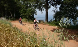 Zwei Radfahrer radeln auf einem mit Sand befestigten Weg entlang