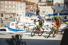 Mountainbiker biegen um die Ecke im Hafen von Cres auf der gleichnamigen Insel in der Kvarner Bucht von Kroatien