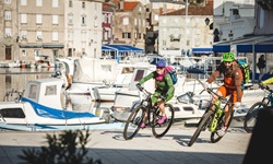 Mountainbiker biegen um die Ecke im Hafen von Cres auf der gleichnamigen Insel in der Kvarner Bucht von Kroatien