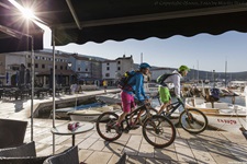 Zwei Mountainbiker erreichen nach erfolgreich absolvierter Tagesetappe den Hafen und bewältigen die letzten Meter, die sie noch vom Schiff trennen.