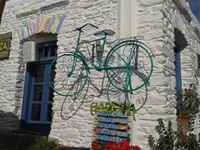 Ein grünes Fahrrad hängt neben dem Eingang zum Restaurant "Gazoza" auf der Kykladeninsel Kythnos an der Hauswand.