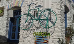 Ein grünes Fahrrad hängt neben dem Eingang zum Restaurant "Gazoza" auf der Kykladeninsel Kythnos an der Hauswand.