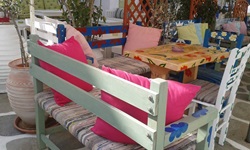Bänke und Stühle mit bunten Kissen vor einem Restaurant auf der Kykladeninsel Kythnos.