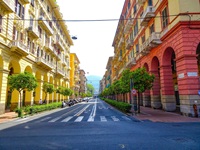 Rote und gelbe Häuser mit Arkadengängen säumen eine breite Straße in La Spezia.