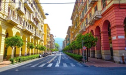 Rote und gelbe Häuser mit Arkadengängen säumen eine breite Straße in La Spezia.