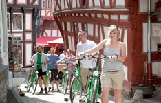 Eine Radlergruppe schiebt ihre Fahrräder durch die von Fachwerkhäusern geprägte historische Altstadt von Limburg.