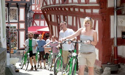 Eine Radlergruppe schiebt ihre Fahrräder durch die von Fachwerkhäusern geprägte historische Altstadt von Limburg.