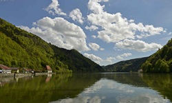 Wunderschöne Flusslandschaft an der Donau mit bewaldeten Ufern und kleinen Dörfern.