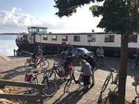 Die Passagiere der MS Lena-Maria machen sich in Huizen vor dem im Hintergrund vor Anker liegenden Schiff für die tägliche Radtour fertig.