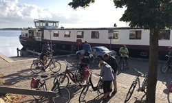 Die Passagiere der MS Lena-Maria machen sich in Huizen vor dem im Hintergrund vor Anker liegenden Schiff für die tägliche Radtour fertig.