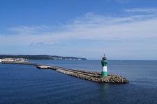 Blick auf einen Deich, an dessen Ende ein türkis-weißer Leuchtturm steht