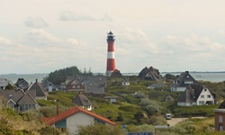 Blick auf einen rot-weißen Leuchtturm auf der Radstrecke von Hamburg nach Sylt