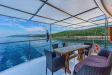 Das überdachte Deck mit Tisch und grauen Loungemöbeln des Komfortschiffes Linda
