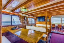 Der mit Holztischen und -bänken ausgestattete Salon des Komfortschiffes Linda