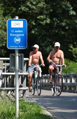 Zwei mit kurzer Hose bekleidete Männer radeln über eine Brücke an eine Kreuzung