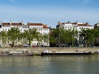 Blick über die Rhone, auf der ein Schiff angelegt ist, zur Promenade von Lyon