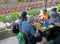 Gäste essen auf einer Terrasse in einem mallorquinischen Restaurant zu mittag - im Hintergrund sind Fahrräder an einer Mauer abgestellt