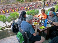 Gäste essen auf einer Terrasse in einem mallorquinischen Restaurant zu mittag - im Hintergrund sind Fahrräder an einer Mauer abgestellt