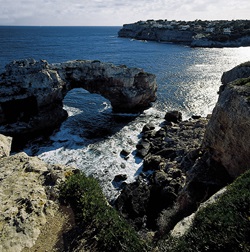 Blick auf eine Schlucht und das Felsentor "Es Pontas", eine natürliche Brücke im Meer