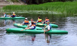 Vier grüne, jeweils mit zwei Personen besetzte Paddelboote auf dem Flusslauf der Kruttinna.