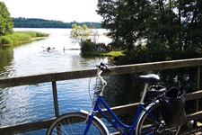 Ein Fahrrad lehnt an einem Brückengeländer, im Hintergrund macht die zugehörige Reisegruppe ihr Mittagspicknick.