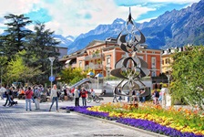 Blumenschmuck und Kunst in der von majestätischen Bergen überragten Fußgängerzone von Meran.