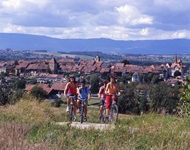 Vier Radfahrer auf der Mittellandroute lassen die Stadt Avenches und die Bergkette des Juragebirges hinter sich.