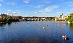 Blick über die Moldau, die von einigen Tretbooten befahren wird, bis zur Karlsbrücke in Prag