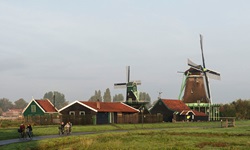 Eine Gruppe Fahrradfahrer radelt auf einem Weg an Windmühlen vorbei