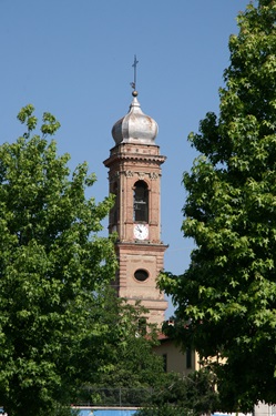 Von Bäumen eingerahmter Kirchturm mit Zwiebeldach.