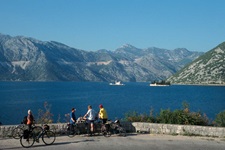 Radfahrer stehen an einer Mauer und blicken auf die Bucht von Kotor