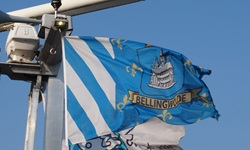 Eine blau-weiße Flagge mit dem Wappen des niederländischen Dorfes Bellingwolde weht im Wind.