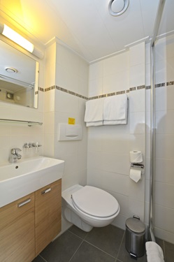 Ein Badezimmer mit WC, Waschtisch und Dusche auf der MS Normandie