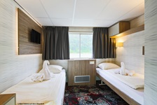 Blick in eine Zwei-Bett-Kabine der MS Normandie mit aus Handtuch geformten Schwänen auf den Matratzen