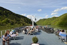 Gäste genießen auf Stühlen und Liegen das Wetter auf dem Sonnendeck der MS Normandie