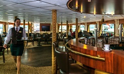 Eine Kellnerin in der Bar der MS Princess mit einem voll beladenen Tablett.